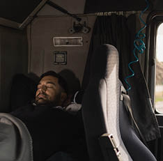 Tired truck driver sleeping in cabin bed on truck stop